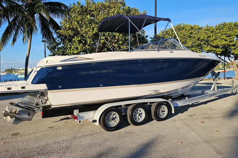 Slide: The Image of 2008 Regal 2700 ES Bowrider boat on trailer, parked near waterfront with palm trees. - 2