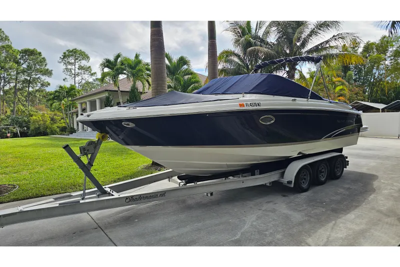 Slide: The Image of 2008 Regal 2700 ES Bowrider on trailer, parked in a driveway with lush greenery. - 78