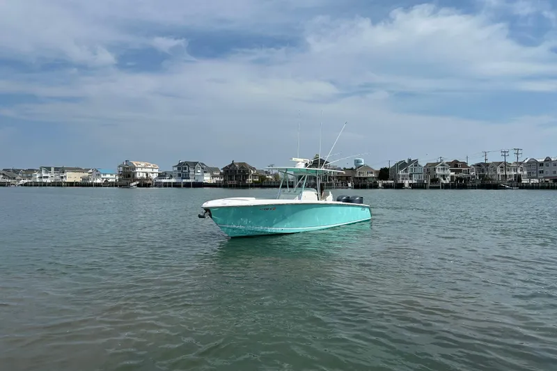 Slide: The Image of Turquoise 2010 Jupiter 34 FS boat on calm water with coastal houses in the background. - 6