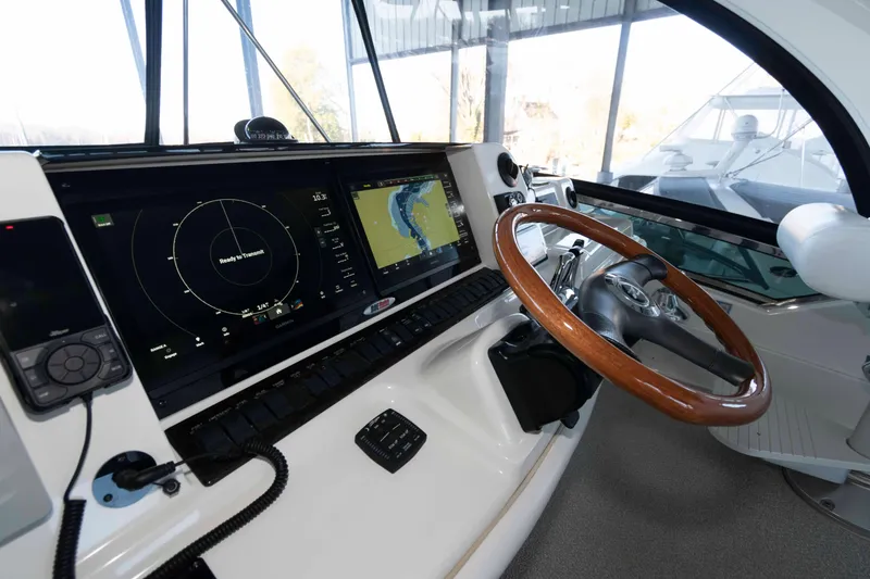 Slide: The Image of 2008 Sea Ray 52 Sedan Bridge helm with navigation screens and wooden steering wheel. - 14