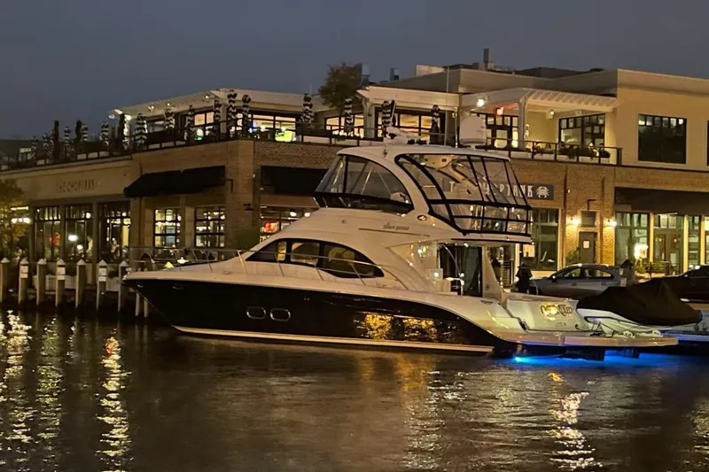 Slide: The Image of 2008 Sea Ray 52 Sedan Bridge yacht docked at night, illuminated by blue lights. - 2