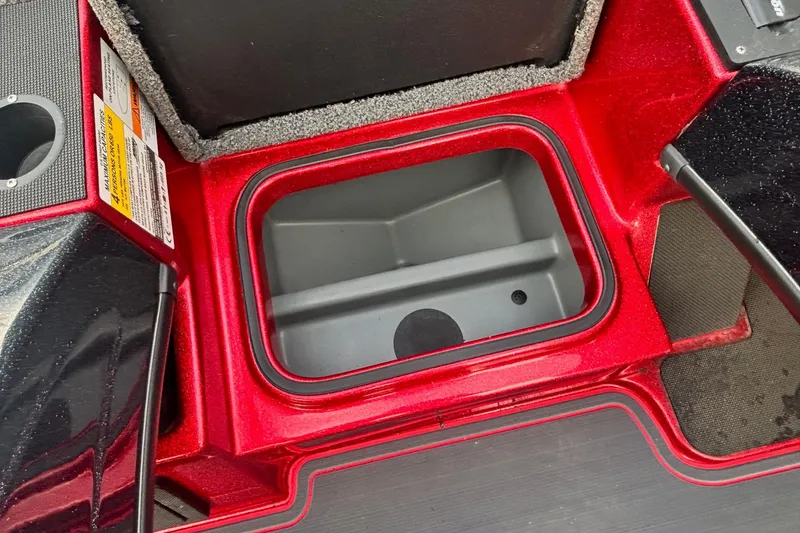 Slide: The Image of 2024 Triton 19 TrX Patriot boat storage compartment, red interior, open lid view. - 6