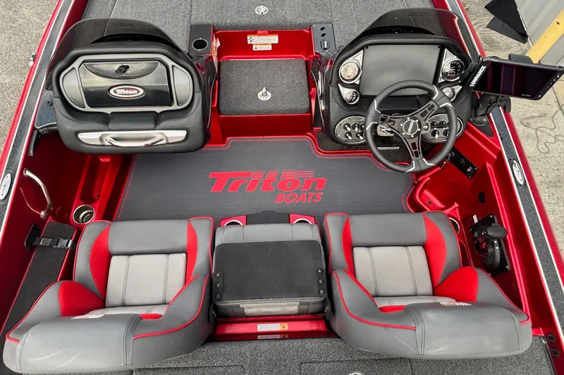 Slide: The Image of 2024 Triton 19 TrX Patriot boat interior with red and gray seating, steering console, and branding. - 9