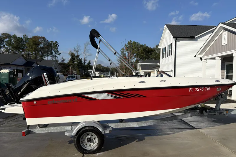 Slide: The Image of 2023 Bayliner Element E18 boat on trailer, red and white design, parked in residential area. - 3