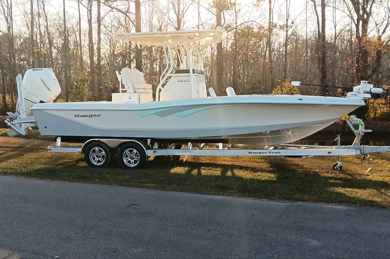 The Image of 2026 Ranger 2660 Bay boat on trailer, parked outdoors in a wooded area. - 0