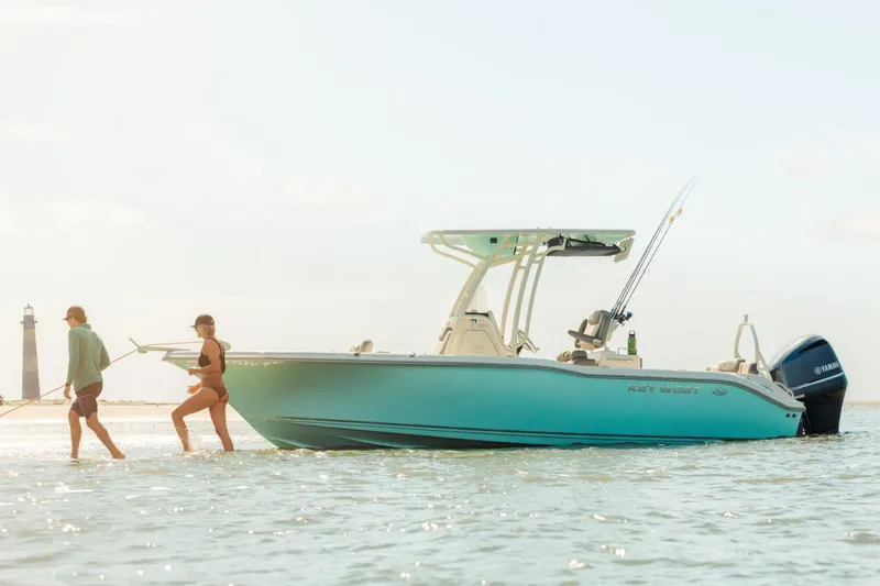Slide: The Image of Manufacturer Provided Image: 2025 Key West 239 FS boat in shallow water with two people, lighthouse in background. - 9