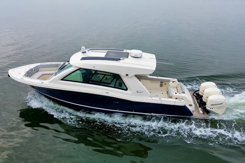 Slide: The Image of 2023 Scout 350 LXZ boat cruising on calm water, featuring triple Mercury engines. - 15