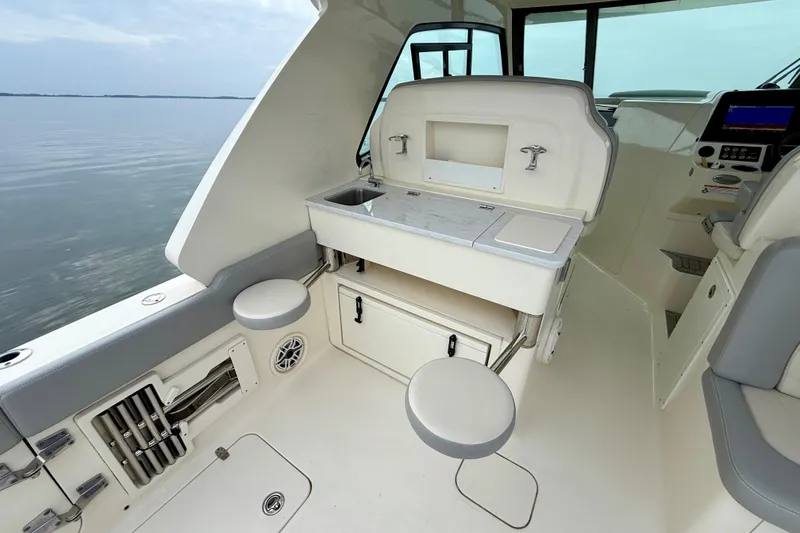 Slide: The Image of 2023 Scout 350 LXZ boat interior with seating and storage, overlooking calm waters. - 40