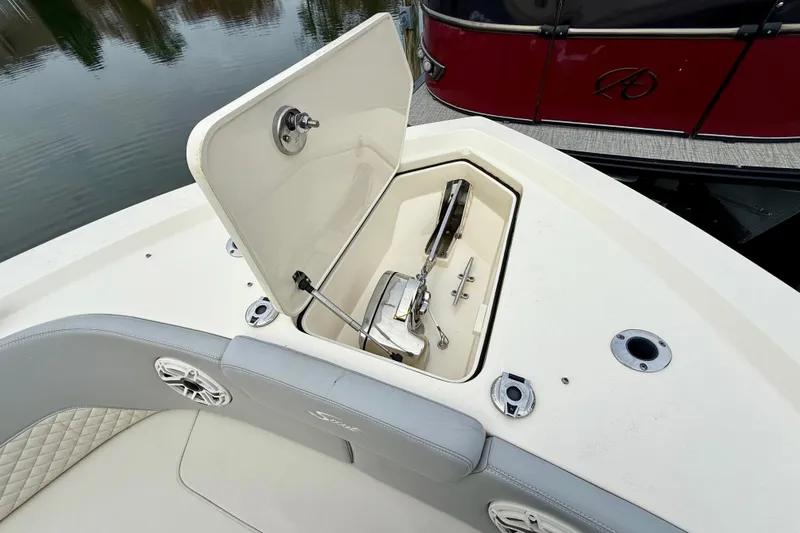 Slide: The Image of 2023 Scout 350 LXZ boat anchor compartment with open hatch, docked near water. - 52