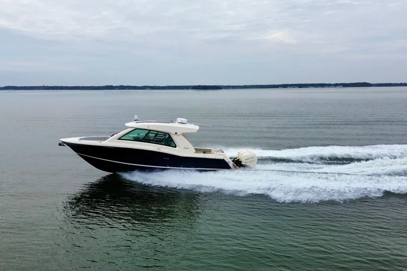 Slide: The Image of 2023 Scout 350 LXZ boat cruising on calm waters under cloudy skies. - 7
