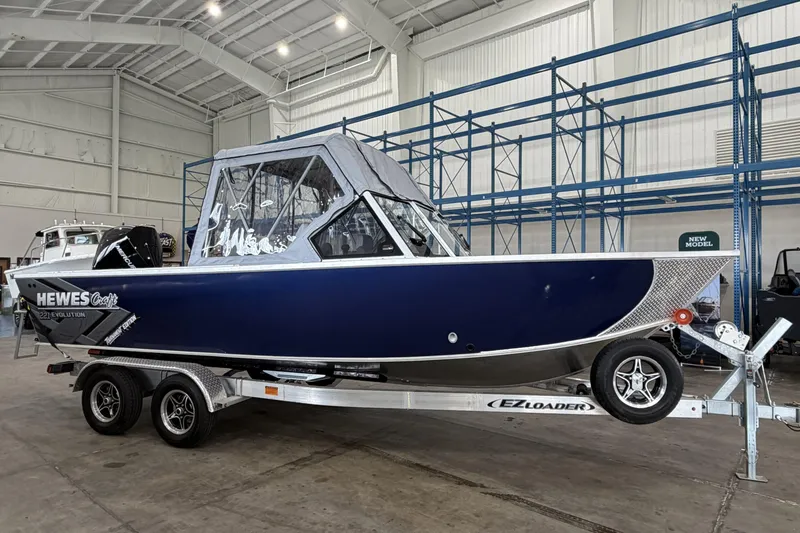 Slide: The Image of 2026 Hewescraft 221 Evolution boat on trailer in indoor showroom. - 2