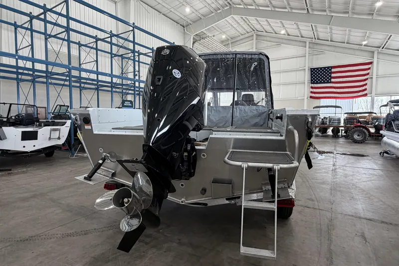 Slide: The Image of 2026 Hewescraft 221 Evolution boat in warehouse with American flag backdrop. - 3