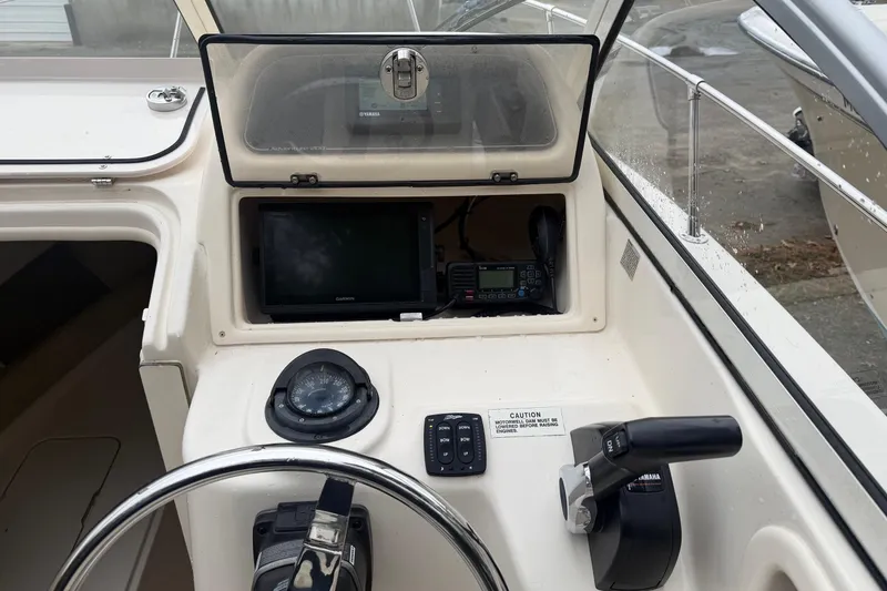 Slide: The Image of 2020 Grady-White Adventure 208 boat dashboard with steering wheel, compass, and navigation controls. - 6