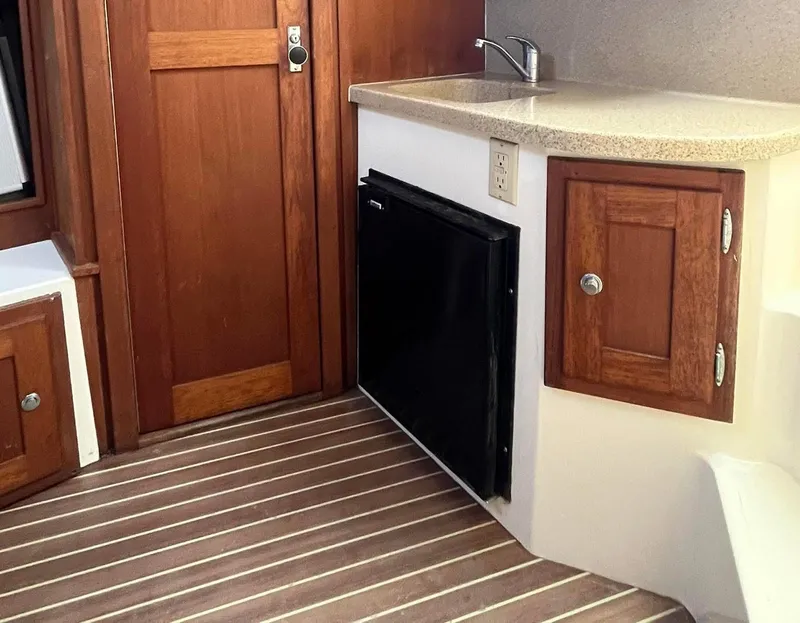 Slide: The Image of 2005 Albemarle 310 Sport Fisherman interior with wood cabinets, compact fridge, and sink. - 8