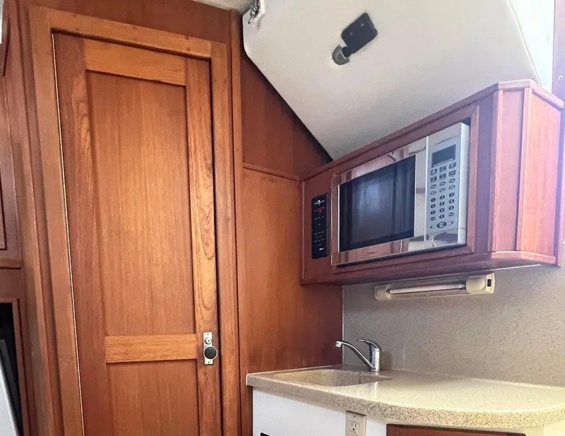 Slide: The Image of 2005 Albemarle 310 Sport Fisherman interior with wood cabinetry, microwave, and sink. - 9
