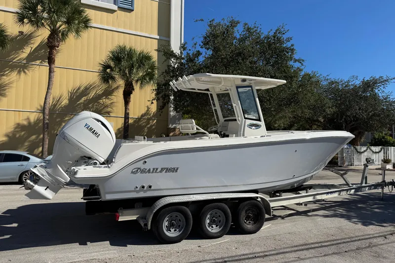 Slide: The Image of 2026 Sailfish 252 CC boat on trailer with Yamaha engine, parked near palm trees. - 19