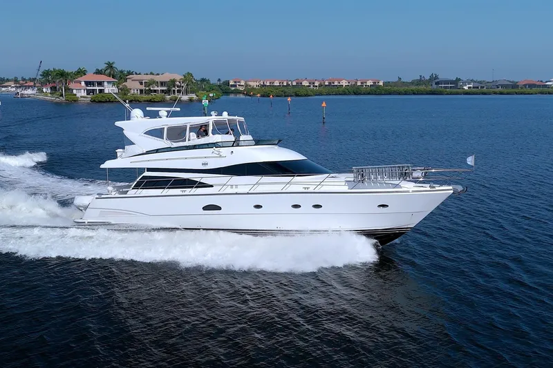 The Image of 2005 Neptunus 62 Flybridge yacht cruising on a sunny day, near waterfront homes. - 0