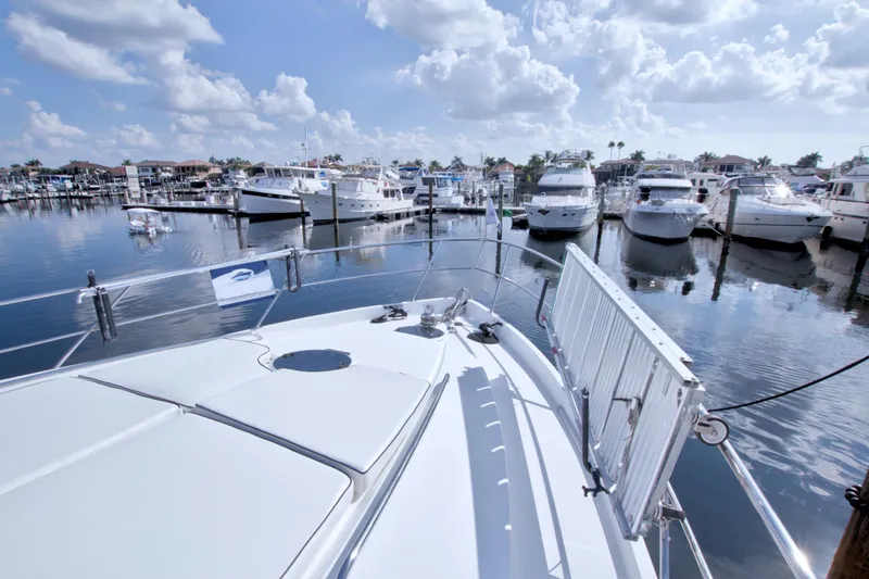 Slide: The Image of 2005 Neptunus 62 Flybridge yacht docked in a sunny marina with calm waters. - 11