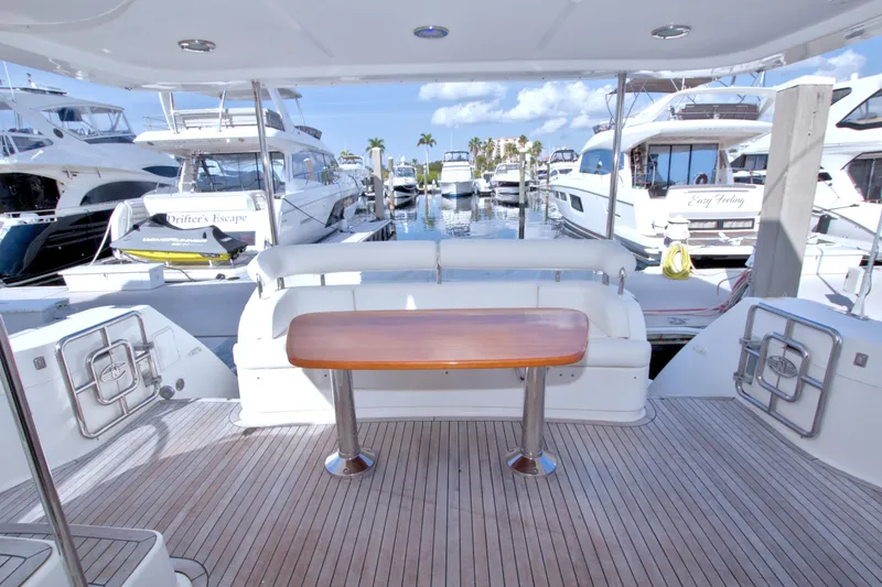 Slide: The Image of 2005 Neptunus 62 Flybridge yacht deck with wooden table, marina view. - 118