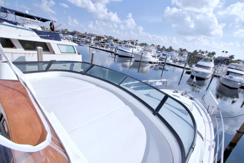 Slide: The Image of 2005 Neptunus 62 Flybridge yacht docked in a marina under a clear blue sky. - 28