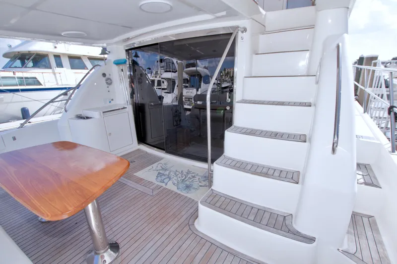 Slide: The Image of Luxurious 2005 Neptunus 62 Flybridge yacht deck with wooden table and stairs. - 34