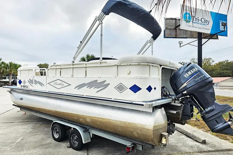Slide: The Image of 2004 Bentley Pontoons 240 Fish on trailer with Yamaha outboard motor, parked outdoors. - 6