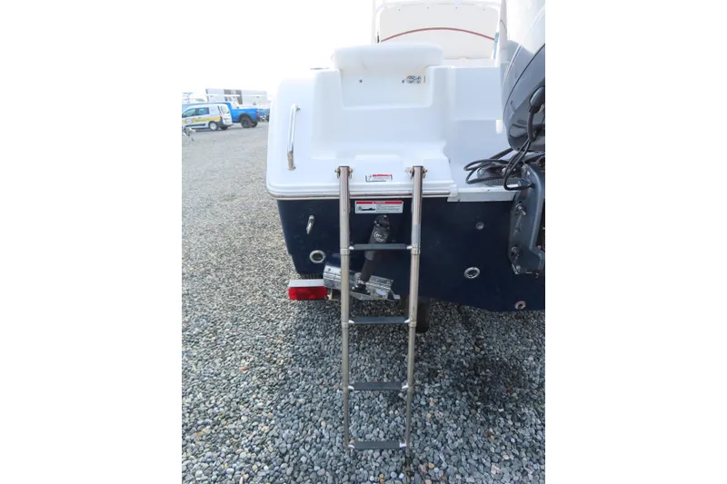 Slide: The Image of 2019 Sea Hunt Ultra 234 boat with rear ladder on gravel surface. - 6