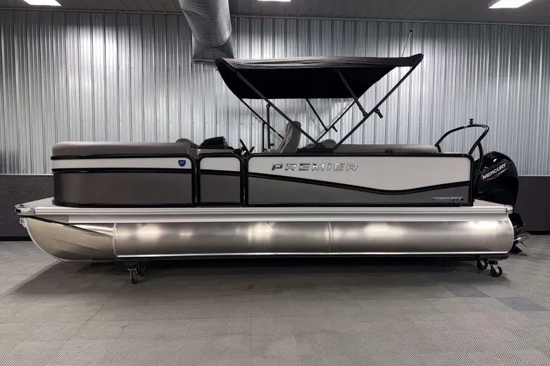 Slide: The Image of 2026 Premier 210 Sunsation RF Tritoon boat in showroom, side view. - 3