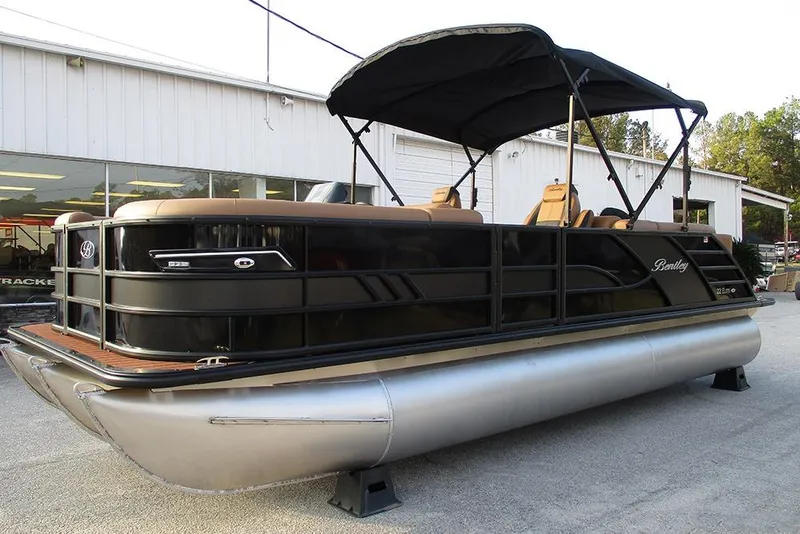 Slide: The Image of 2026 Bentley Pontoons Elite 223 Admiral pontoon boat with canopy, displayed outdoors. - 2