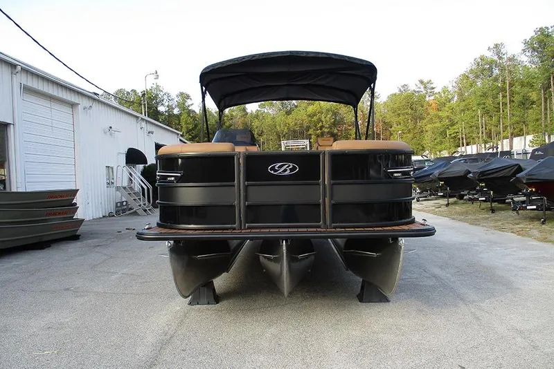 Slide: The Image of 2026 Bentley Pontoons Elite 223 Admiral, black, parked outdoors near a warehouse. - 3