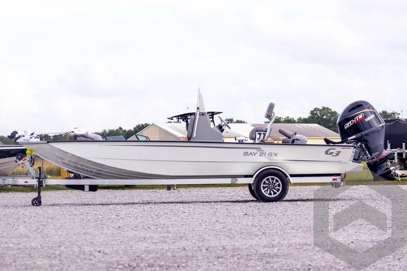 Slide: The Image of 2026 G3 Bay 21 GX boat on trailer with Yamaha outboard motor, parked outdoors. - 7