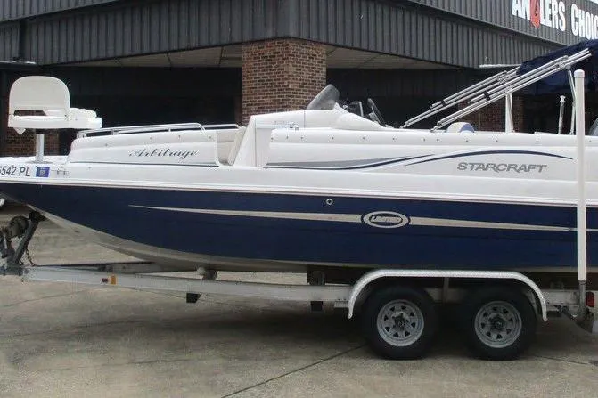 The Image of Starcraft 2009 OB Limited boat on trailer, blue and white design, parked outside. - 1