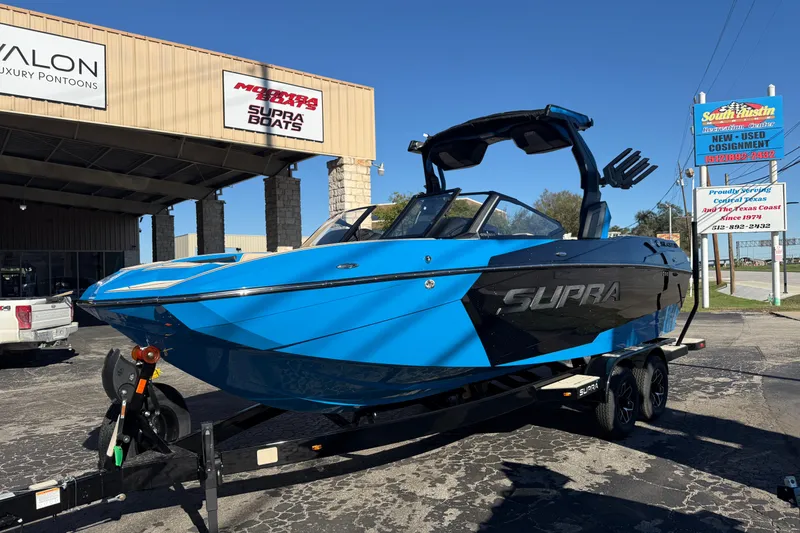 Slide: The Image of 2026 Supra SL 550 boat in blue and black on a trailer at a dealership. - 4