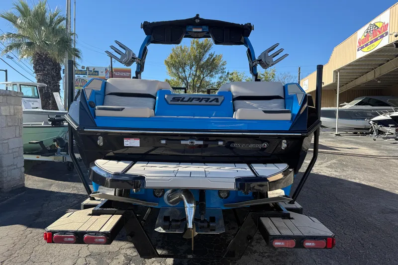 Slide: The Image of 2026 Supra SL 550 boat, blue and white, rear view at a marina. - 7