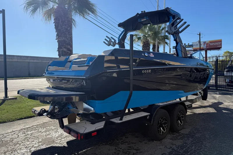 Slide: The Image of 2026 Supra SL 550 boat on trailer, sleek black and blue design, parked outdoors. - 8