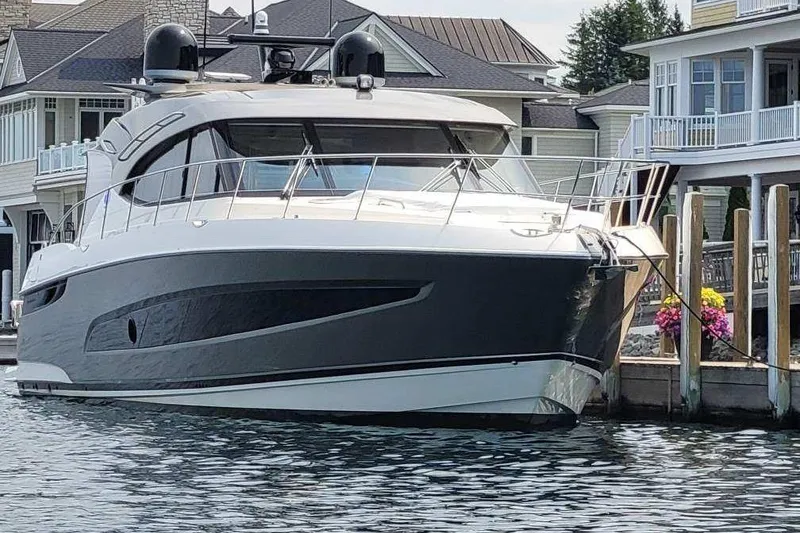 The Image of 2023 Riviera 5400 Sport Yacht docked near waterfront homes. - 0