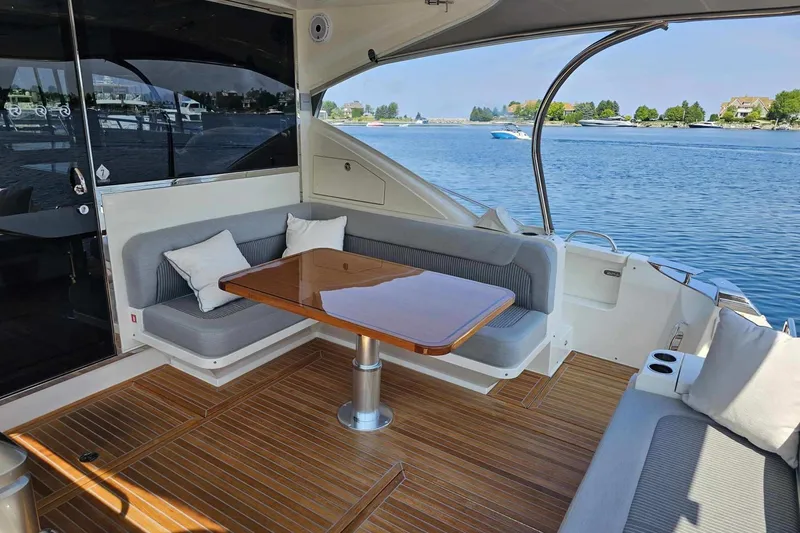 Slide: The Image of 2023 Riviera 5400 Sport Yacht deck with elegant seating and scenic water view. - 5
