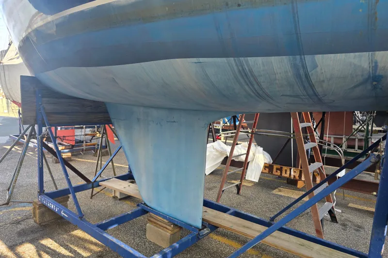 Slide: The Image of 1985 Express Yachting Express 30 sailboat hull on a stand, undergoing maintenance. - 32