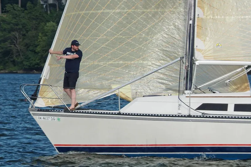 Slide: The Image of 1985 Express Yachting Express 30 sailboat with person adjusting sails on a lake. - 44