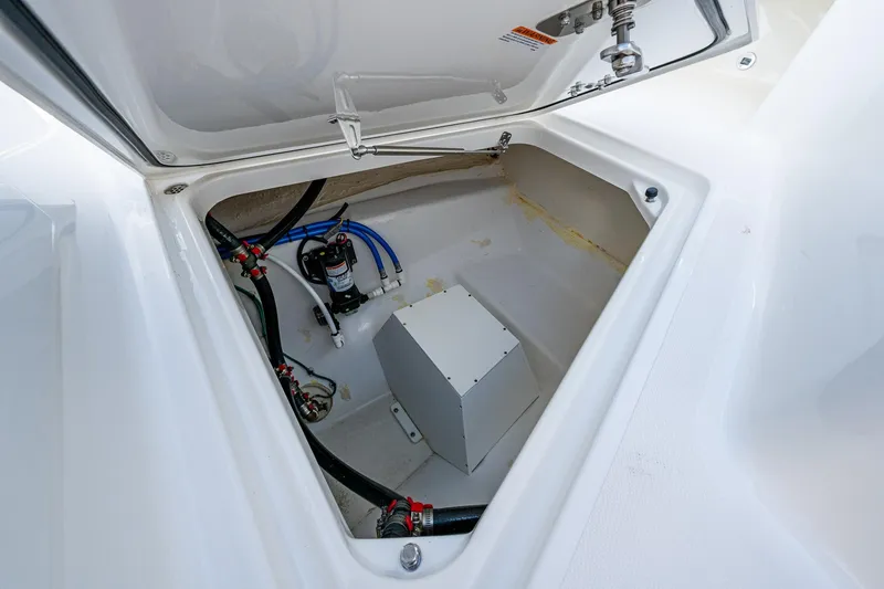 Slide: The Image of 2021 Pursuit S 288 Sport boat storage compartment with wiring and pump system. - 6