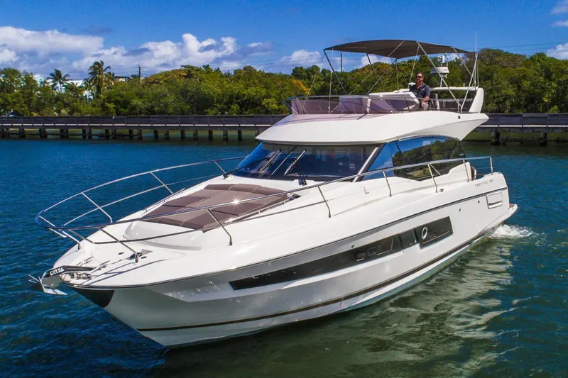 The Image of Luxury 2020 Prestige 460 yacht cruising on a sunny day, surrounded by lush greenery. - 0