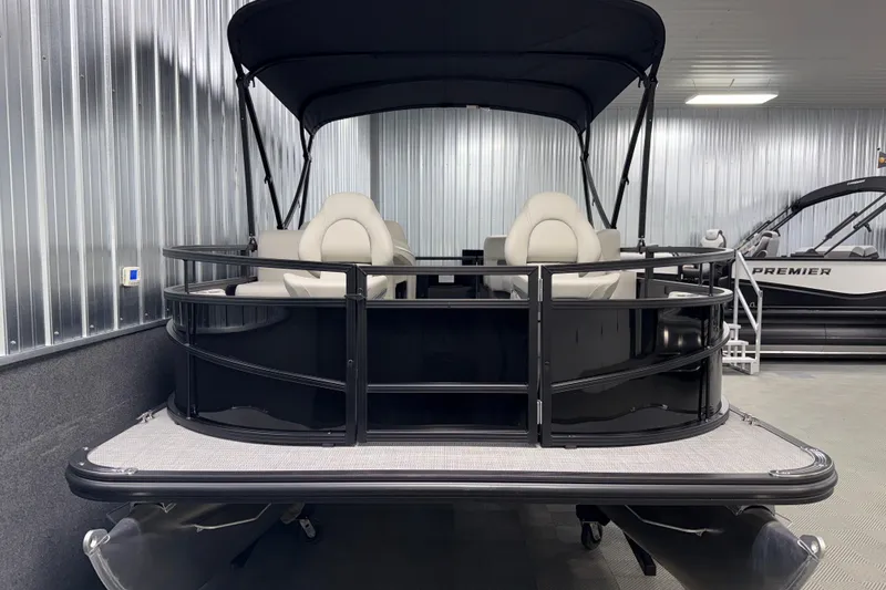 Slide: The Image of 2026 SunChaser Vista 16 Fish pontoon boat in showroom, featuring sleek black design and canopy. - 19
