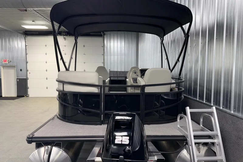 Slide: The Image of 2026 SunChaser Vista 16 Fish pontoon boat in a garage, featuring a Mercury 25 engine. - 22