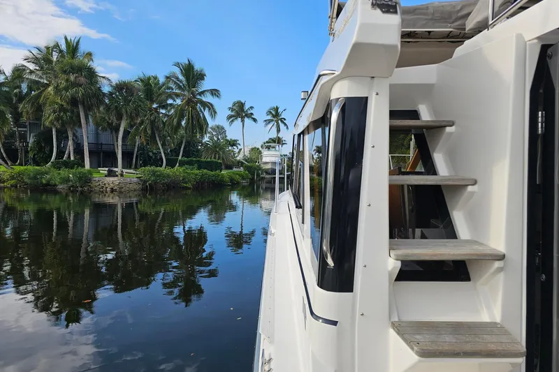 Slide: The Image of 2022 Cuwater C-32-CB boat on a serene river with palm trees and blue sky. - 12