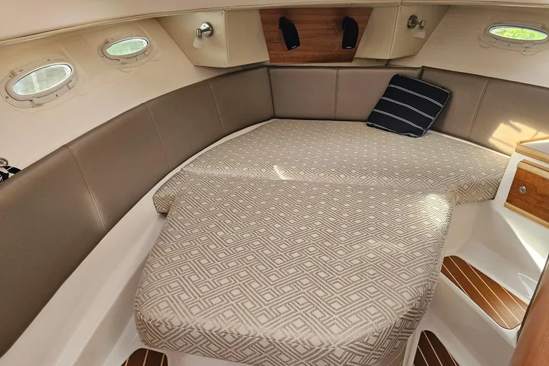 Slide: The Image of 2022 Cuwater C-32-CB cabin interior with patterned bedding and porthole windows. - 18