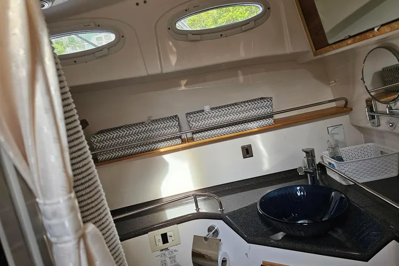 Slide: The Image of Modern boat bathroom with blue glass sink, porthole windows, and sleek countertop. Cuwater C-32-CB 2022 model. - 21