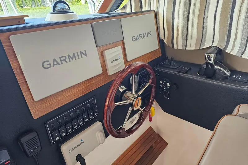 Slide: The Image of Cuwater C-32-CB 2022 boat dashboard with Garmin navigation system and wooden steering wheel. - 23