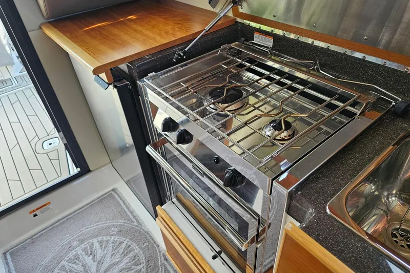 Slide: The Image of Compact kitchen in 2022 Cuwater C-32-CB with stove, sink, and wooden countertop. - 26