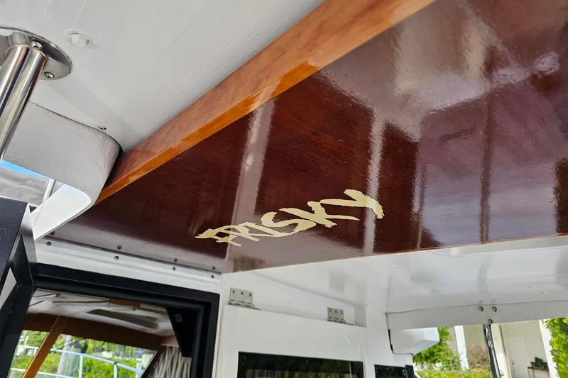 Slide: The Image of Cuwater C-32-CB 2022 boat interior with glossy wood finish and "FRISKY" text. - 35