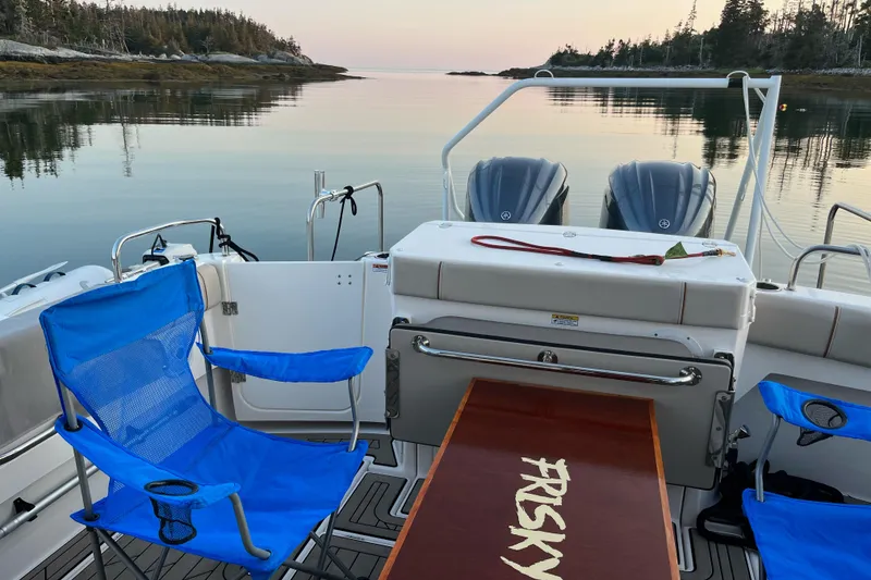 Slide: The Image of Boat interior with blue chairs, table labeled "FRISKY," and serene water view. Cuwater C-32-CB, 2022. - 36